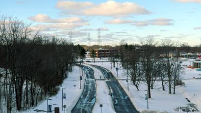 Two roads running along side each other in the snow, with leaveless trees on either side